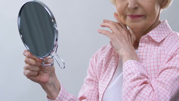 Aged Woman Looking in Mirror, Touching Wrinkled Face, Thinking About Lost Beauty