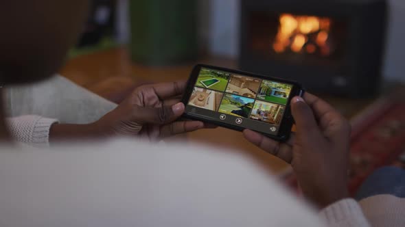 Hands of african american woman using smartphone and lying on sofa