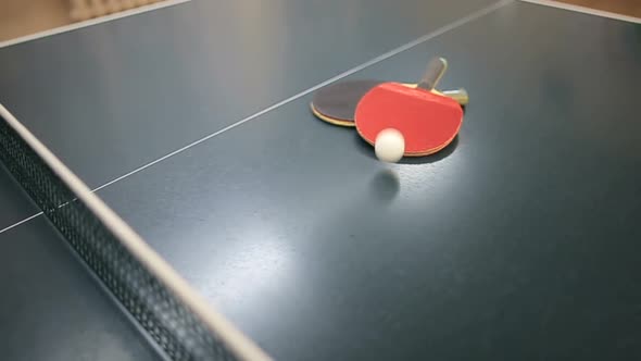 Two Table Tennis or Ping Pong Rackets and Ball on a Blue Table with Net