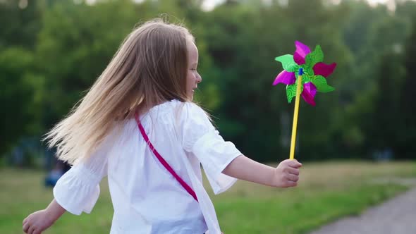 Happy smiling child girl outdoor. Smiling child girl with waving on the wind spreading hands in park