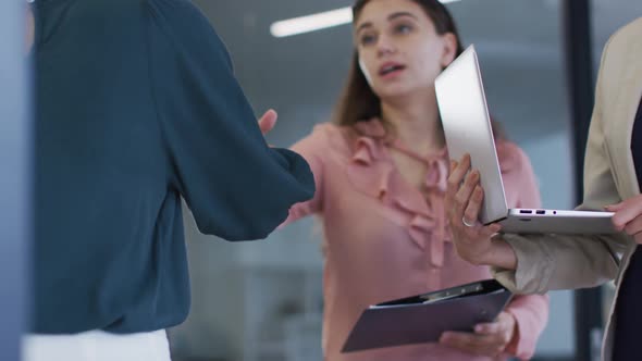 Caucasian businesswoman standing and shaking hands with female colleague at a meeting in office