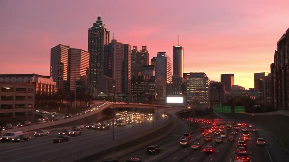 Static, wide, timelapse shot of the Atlanta Skyline with traffic below as the sun goes down.