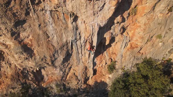 Aerial View From Drone of Strong Muscular Young Man Hanging on Rope and Descenting After Climbing on