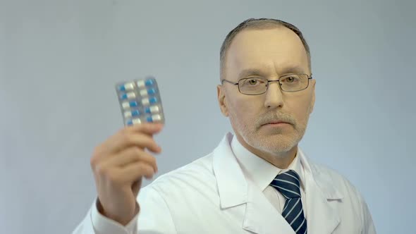 Serious Physician Holding Pills in Hand, Recommending Effective Medication