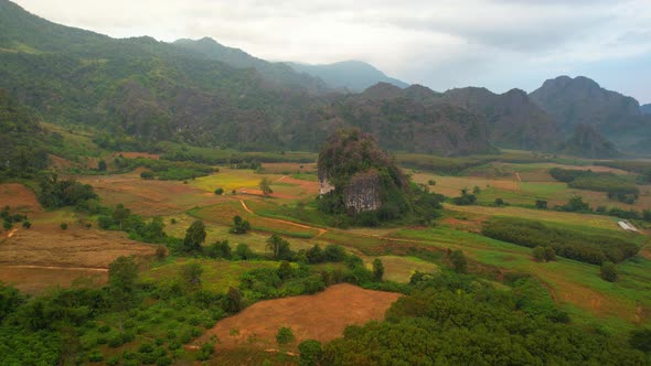 Aerial view a drone fly over a rural area with mountains in the background at sunrise.