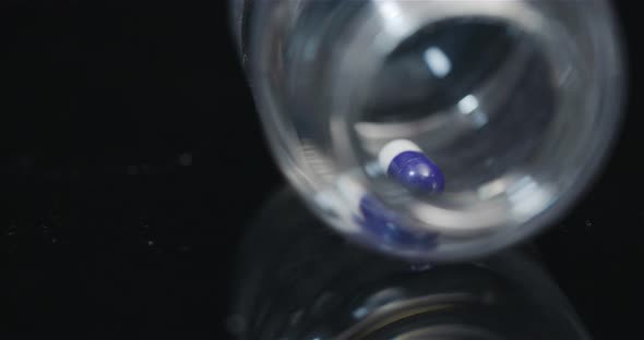 Single Medical Pill in Small Bottle Rotating on Black Background