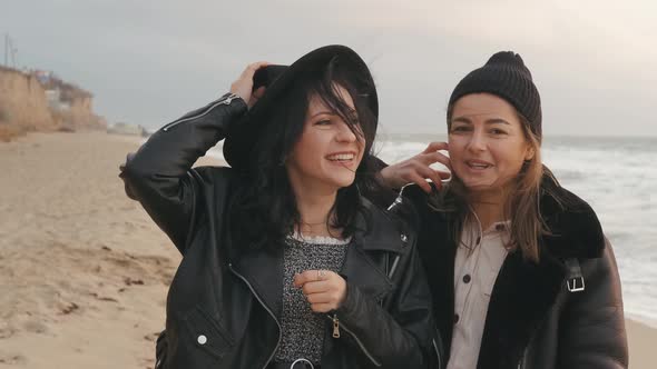 Couple of Beautiful Young Women Walking on the Beach on at Sunset