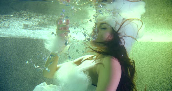 Sexy Woman in White Clothes Is Floating Under Water with Star Garland