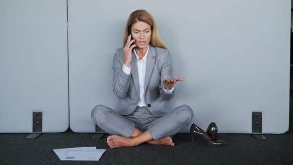 Nervous Tired Businesswoman Talking on the Phone While Sitting on the Floor