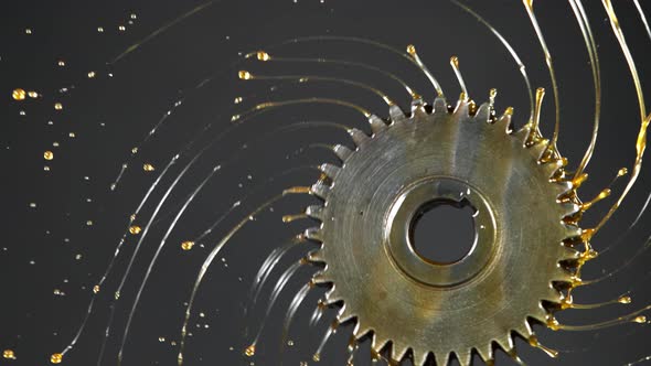 Super Slow Motion Shot of Rotating and Splashing Metal Cogwheel on Dark Background at 1000 Fps.