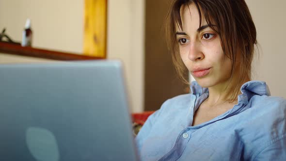 Serious Woman Sits in Living Room and Looking at Computer Screen
