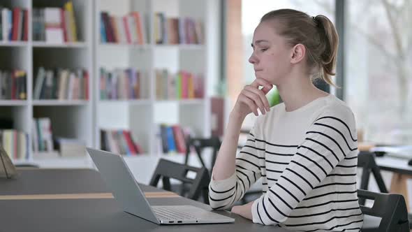 Pensive Young Woman Using Laptop in Library