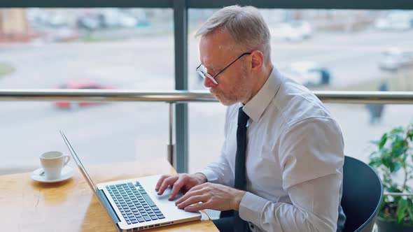 Freelance job. Mature man working on a laptop near the window.