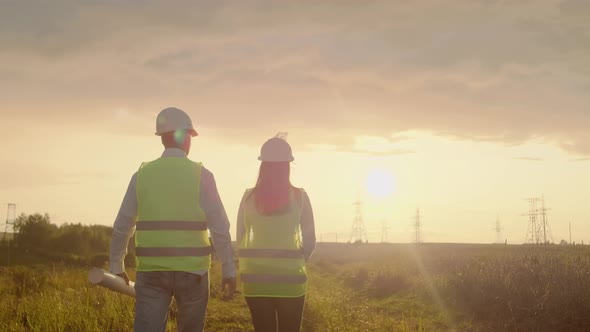 The View From the Back Group of Engineers at a Highvoltage Power Plant with a Tablet and Drawings