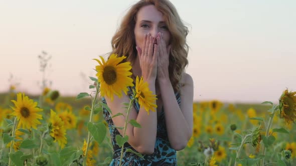 Portrait of a Young Attractive Woman with Red Hair and a Blue Dress in a Field of Sunflowers at