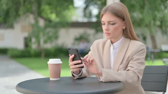 Young Businesswoman Using Smartphone in Outdoor Cafe