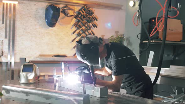 Welding engineer welds an aluminum part using arc welding and argon in a shop in a factory