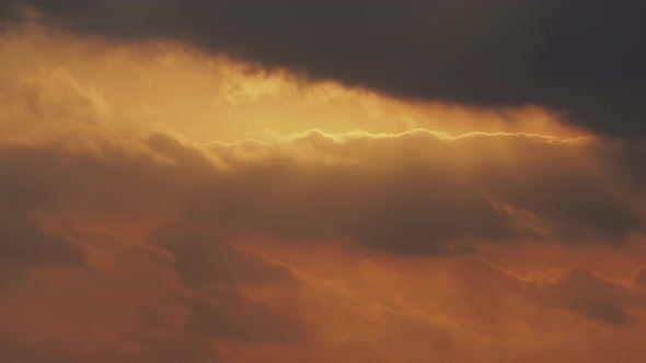 Bright Disk of Sun Moves Through Gapes of Clouds in Shining Sunset Sky