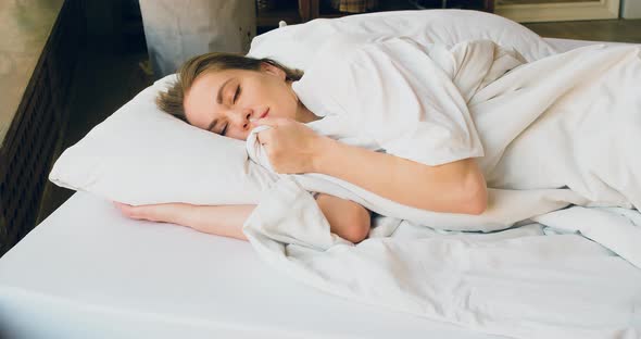 Closeup View of a Woman is Sleeping She Straightens the Blanket Smiles in Her Sleep and Lies Down