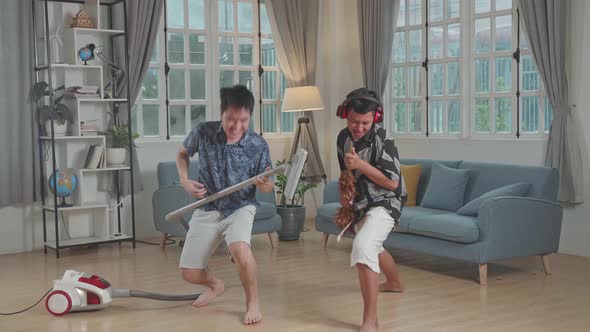 Cheerful Young Asian Father And Son Cleaning Up They Home And Singing