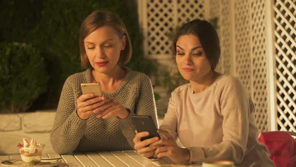 Two Female Friends Looking Photos and Gossiping, Using Mobile App for Social Net