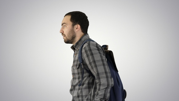 Portrait of man putting backpack on on gradient background.