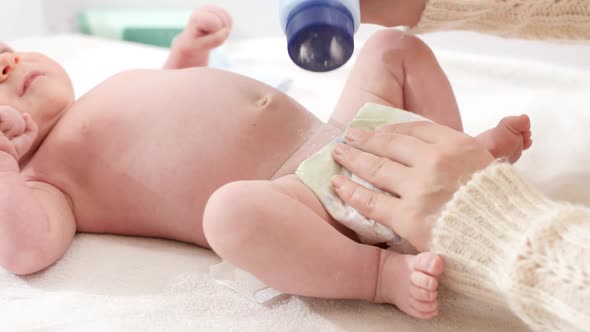 Closeup of Mother Applying Talcum Powder While Changing Messy Diapers of Her Little Baby Son on