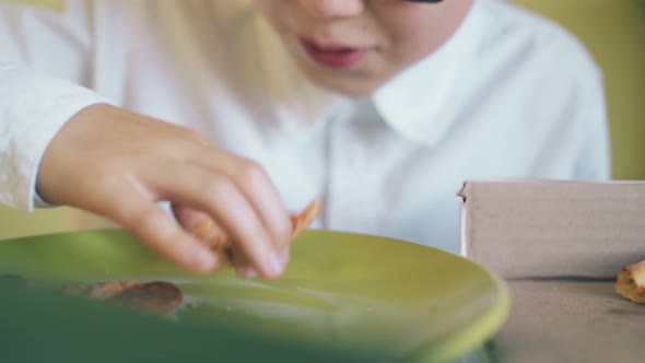 Little Schoolboy Eats Fresh Pizza From Color Plate Closeup