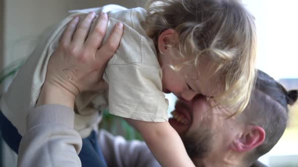 Close Portrait of an Adult Man with a Beard and Fashionable Hairstyle Hugs Have Fan with His Little