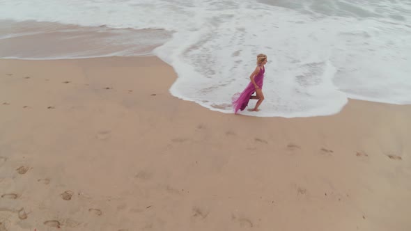 Woman In A Dress Wandering On The Beach