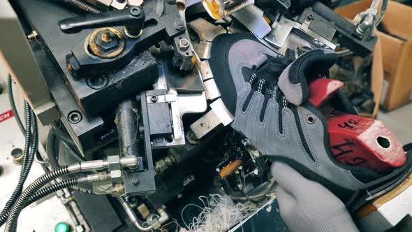 Factory Worker Using a Shoe Making Machine at a Footwear Facility. Close Up