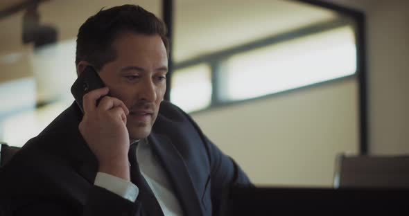 Close up of a businessman talking on the phone while working from his office. Slow motion