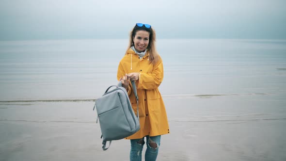 A Tourist Woman Is Putting on a Backpack and Smiling