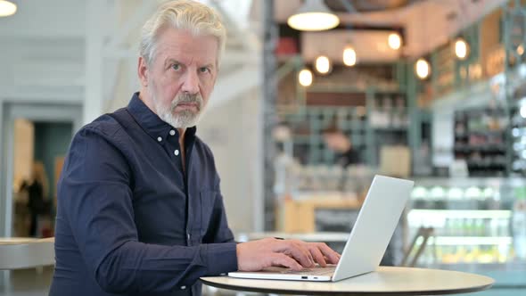 Thumbs Down By Old Man Using Laptop in Cafe