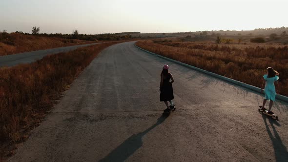 Young Ladies Are Longboarding on a Country Road in the Evening, 