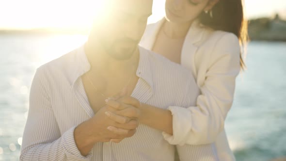 Hispanic Couple Holding Hands on Embankment in Sunshine
