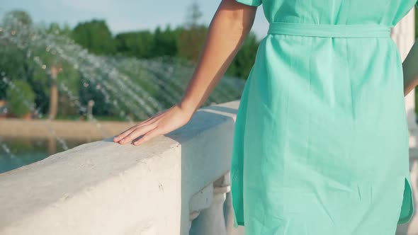 young beautiful girl walking in the spring or summer park. Passes along the bridge holding a hand on