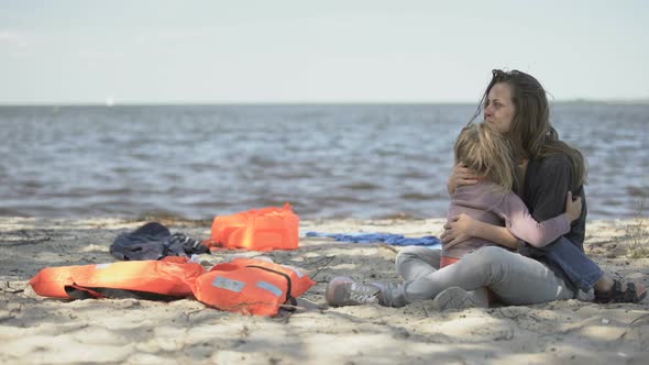 Mother and Daughter Crying and Embracing on Seashore, Survived Tornado Together