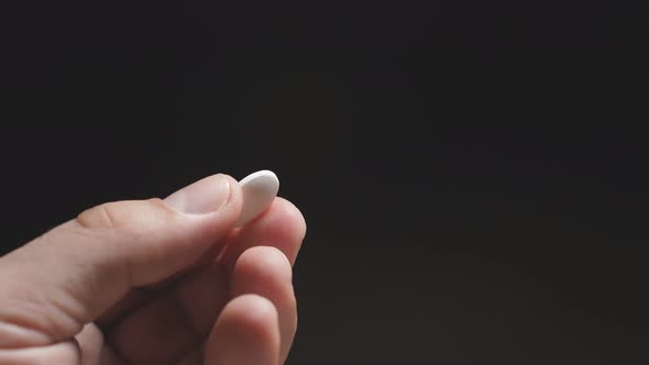 Close-up of a White Tablet in a Man's Hand on a Dark Background