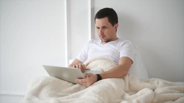 Man Browsing Web on Laptop When Lying in Bed