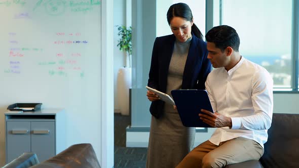 Business colleagues discussing over digital tablet and clipboard