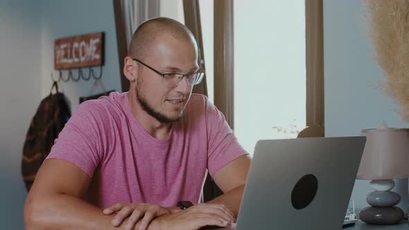 Young handsome man sitting in cafe with laptop making video calling by webcam