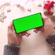 Man holding smartphone with vertical green screen on Christmas background with gifts. - VideoHive Item for Sale