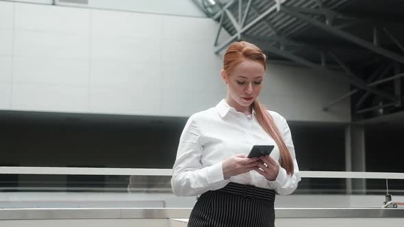 woman with a phone is standing in the lobby of a business center