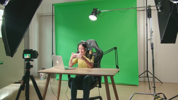 Excited Asian Kid Girl Playing Video Game With Mobile Phone While Live Stream On Green Screen