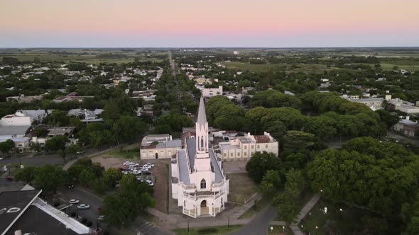 Aerial shot flying over beautiful white church on Villa Elisa town, Argentina at dusk
