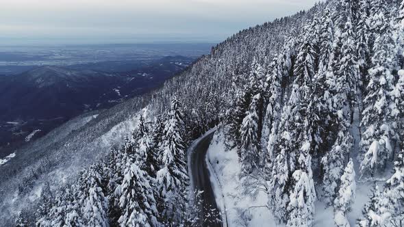 Aerial View of a Desert Road Along Snowed Mountain Side