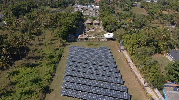Giant Solar Panels Farm Field At Sunshine on exotic island.Aerial Flight Birds Eye backwards.