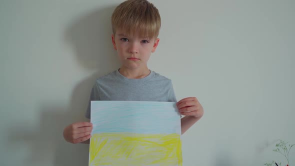 A Little Boy Cries and Raises a Painted Ukrainian Flag