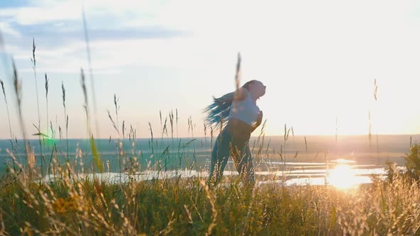 Woman with Long Braids Dancing on Sunset Wheat Field